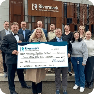 A group of people from both Rivermark and Rebuilding Together showing off a large $3 million dollar check.