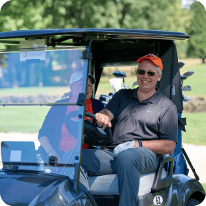 Man sitting in golf cart smiling.