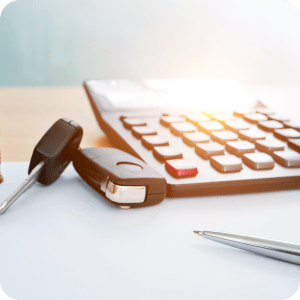 Car keys sitting on a desk next to a calculator.