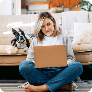 Woman sitting on the floor looking at a laptop.