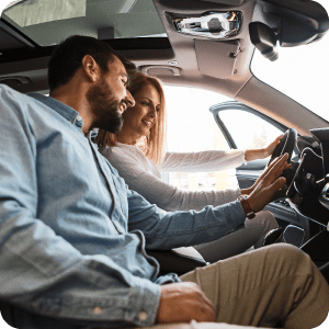Couple sitting in a car together with the door open.