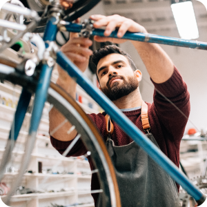 Small business owner working on tightening the handle bars of a bicycle.