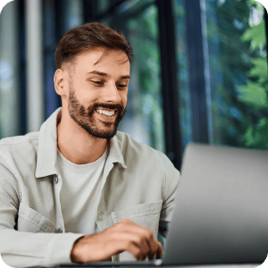 A person working on a laptop and smiling.