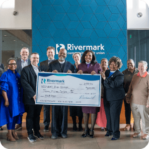 A group of people from both Zion Church and Rivermark holding a large Rivermark check.