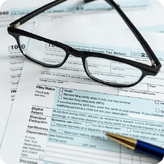 Reading glasses sitting on a 1040 tax form with a pen in the corner.