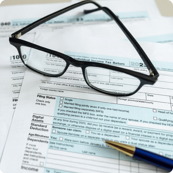 Reading glasses sitting on a 1040 tax form with a pen in the corner.