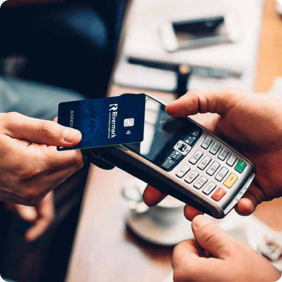 A person tapping a credit card to a payment processing machine.