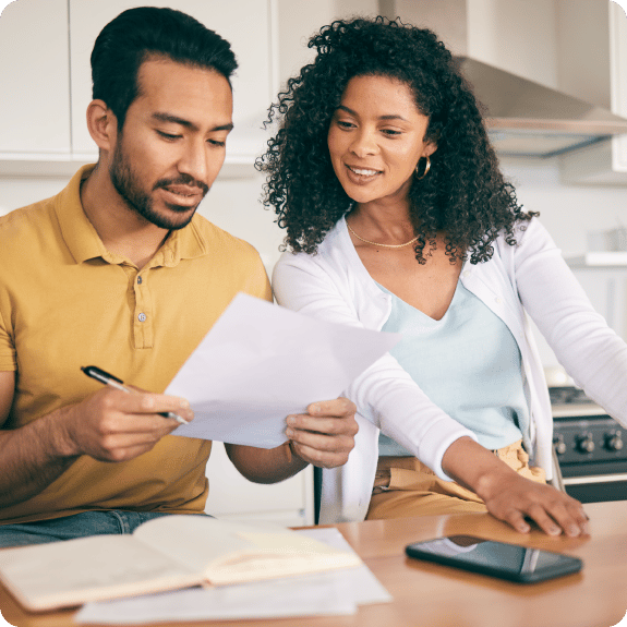A man and a woman are looking over a document in the kitchen.