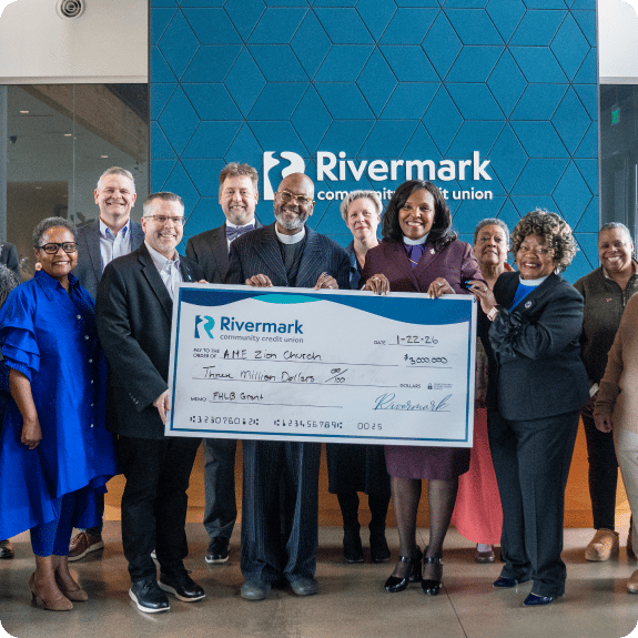 A group of people from both Zion Church and Rivermark holding a large Rivermark check.