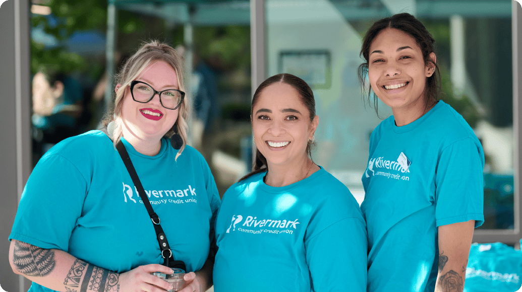 Three Rivermark employees with blue Rivermark shirts smiling at the camera.