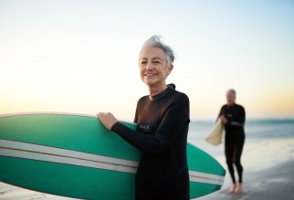 Older couple surfing at the beach.