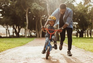 Father helping his son ride a bike without training wheels.
